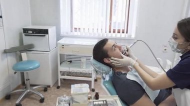 Dişçi genç kadın erkek hastaya diş ofisinde yordamlar yapma. Sağlıklı yaşam kavramı