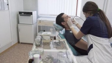 Dişçi genç kadın erkek hastaya diş ofisinde yordamlar yapma. Sağlıklı yaşam kavramı