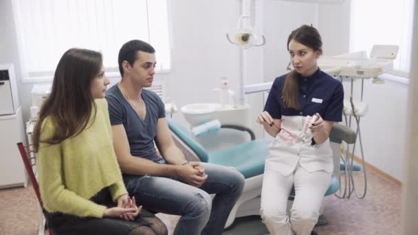 O familie fericită în vizită la cabinetul stomatologic. Medicul dentist vorbeste cu pacientii de sex masculin si feminin. Conceptul de viață de familie sănătoasă — Videoclip de stoc