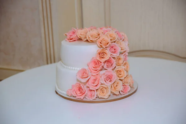 Gâteau de mariage avec des roses sur table blanche — Photo