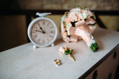 Düğün aksesuarları. Yaka çiçeği, altın yüzük, beyaz dokulu masaya çiçek güzel bir buket. Gelin ve damat süsleme kavramı