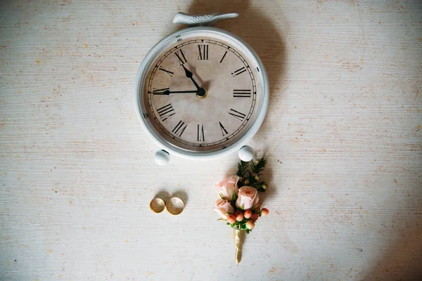 Svatební doplňky. Boutonniere, zlaté prsteny, krásnou kytici květin na bílé strukturované tabulka. Koncept nevěsty a ženicha zdobení — Stock fotografie