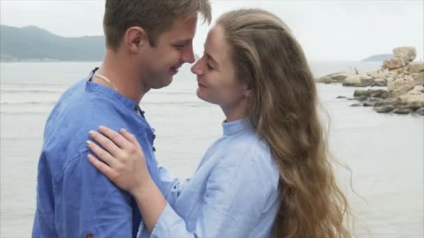 De cerca, el hombre acaricia a una chica por el pelo, la abraza y la besa. Un par de amantes descansan en el mar — Vídeo de stock