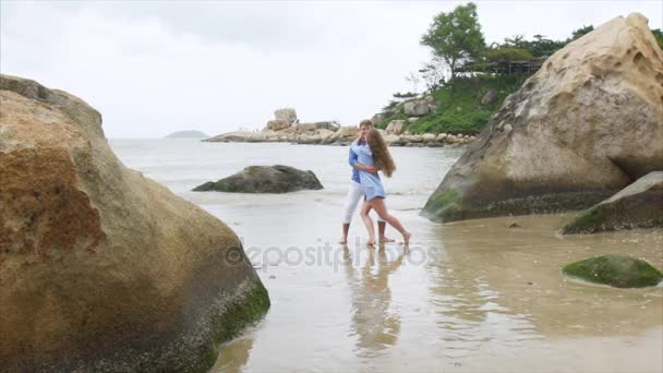 Un homme encercle une fille dans ses bras sur une plage de sable marin. Une paire d'amoureux tourbillonnent au ralenti — Video