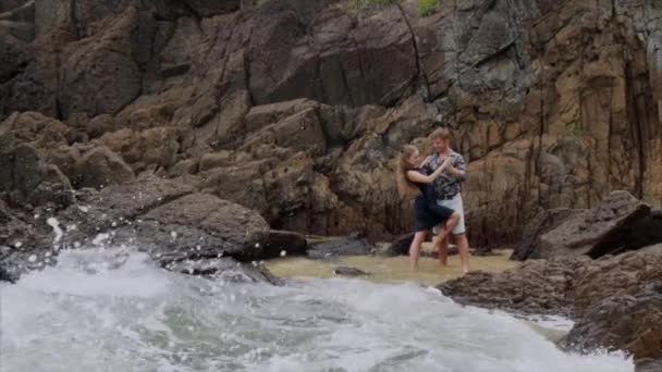 Медленное движение, девушка танцует на берегу океана и держит мужчину за руку. Вид на морской пляж с волнами — стоковое видео