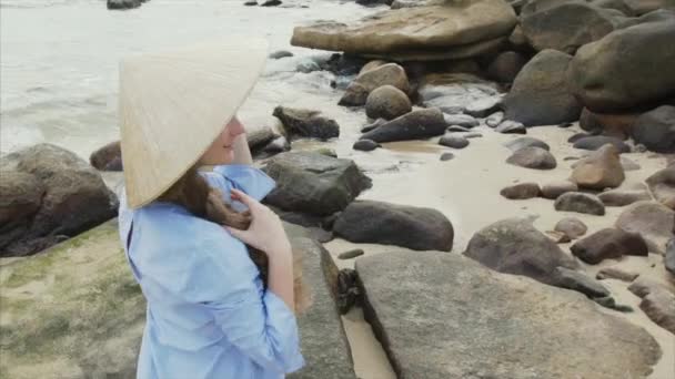 Una chica con un vestido azul se pone un sombrero vietnamita. Un hombre se acerca a una chica y un par de amantes abrazan — Vídeos de Stock