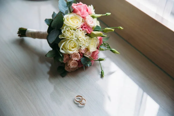 Anillos de boda y ramo de rosas sobre fondo — Foto de Stock