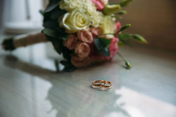 Anillos de boda y ramo de rosas sobre fondo — Foto de Stock