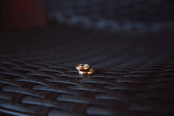 Dos anillos de boda colocados en la mesa oscura — Foto de Stock
