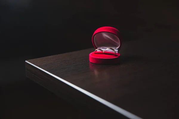 Anelli da sposa dorati in scatola rossa sul tavolo nero — Foto Stock