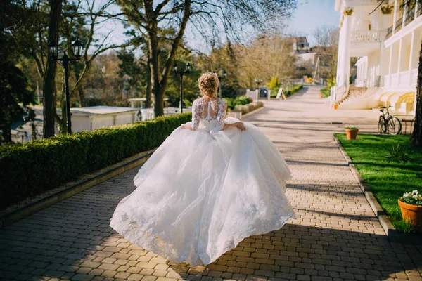A gyönyörű menyasszony, szőke haj, fut, integetett neki ruha esküvő napján. Hátulnézet — Stock Fotó