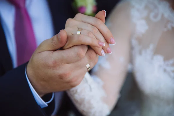 Großaufnahme Bräutigam und Braut halten Händchen am Hochzeitstag und zeigen Ringe. Konzept der Liebesfamilie — Stockfoto