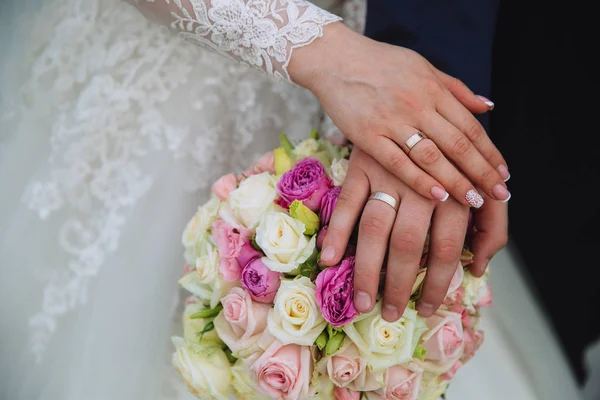 Großaufnahme Bräutigam und Braut halten Händchen am Hochzeitstag und zeigen Ringe. Konzept der Liebesfamilie — Stockfoto
