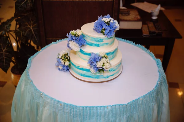 Multilevel bruidstaart op witte tafel. Snoep in witte en blauwe kleur. Bovenaanzicht — Stockfoto