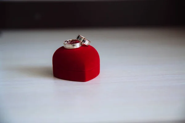 Anillo de boda de compromiso dorado en una caja en forma de corazón sobre fondo de madera blanca — Foto de Stock