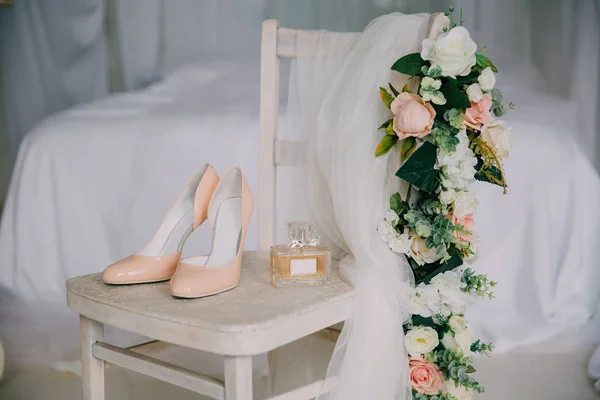 Bridal accessories on a white chair with flowers, perfume shoes. Clothing concept