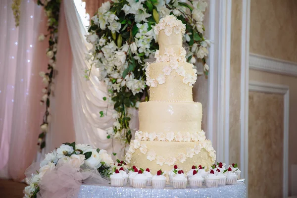 Большой сладкий многоуровневый свадебный торт украшен цветами. Концепция шоколадного батончика на вечеринке — стоковое фото