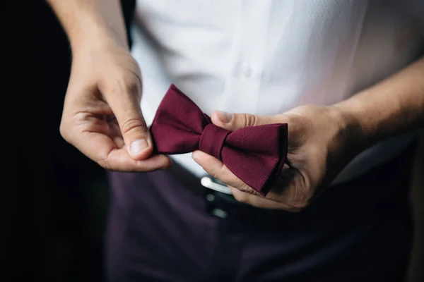 Close-up zakenman bruidegom bedrijf ' bow-tie in zijn handen. Concept van mannen stijlvolle elegantie kleding — Stockfoto