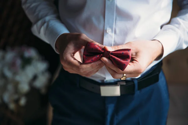 Közelkép üzletember vőlegény csokornyakkendő tartja a kezében. Fogalmának férfiak stílusos eleganciát ruhák — Stock Fotó