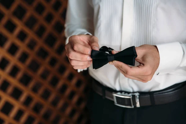 Közelkép üzletember vőlegény csokornyakkendő tartja a kezében. Fogalmának férfiak stílusos eleganciát ruhák — Stock Fotó