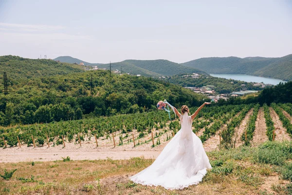 Mától egy luxus fehér ruhában, hátsó nézet. A háttérben a hegyek és szőlőskertek gyűrűjében — Stock Fotó