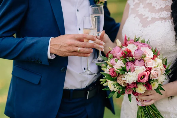 Κοντινό πλάνο του γαμπρού και της νύφης κρατώντας τα χέρια με ένα ποτήρι σαμπάνια κατά την ημέρα του γάμου και δείχνουν δαχτυλίδια. Έννοια της οικογένειας αγάπη — Φωτογραφία Αρχείου