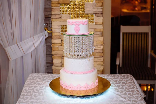 Білий багаторівневий весільний торт, прикрашений рожевими кремовими квітами на столі. Концепція цукерки барі — стокове фото