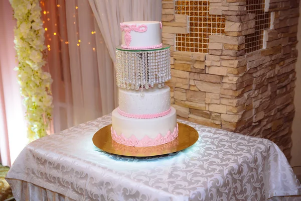 Beyaz çok düzeyli düğün pastası masaya pembe krema çiçek ile dekore edilmiştir. Şeker çubuğu kavramı — Stok fotoğraf