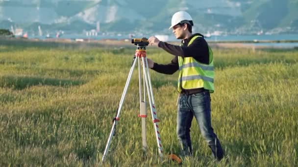 作業服の男性の測量は、建設現場で機器を調整します。ランドス ケープの概念設計、測地学 — ストック動画