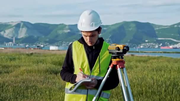 Surveyor inženýr je měření hladiny na staveništi. Geodet zajistit přesné měření před podnik velkých stavebních projektů. Pojetí krajiny design — Stock video