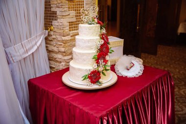 Beyaz çok düzeyli düğün pastası masaya kırmızı krem çiçek ile dekore edilmiştir. Şeker çubuğu kavramı