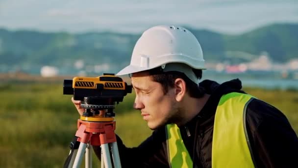 測量技術者は、工事現場のレベルを測定です。測地学者では、大規模な建設事業の前に正確な測定を確認します。ランドス ケープ デザインの概念 — ストック動画