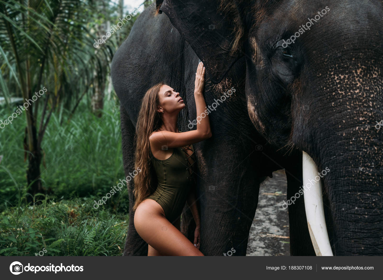 ung kvinde krammer elefant skoven. Smuk pige model med sporty krop udgør i grøn badedragt. Begrebet zoo, tropiske fotosession — Stock-foto © rmano.mail.ru #188307108