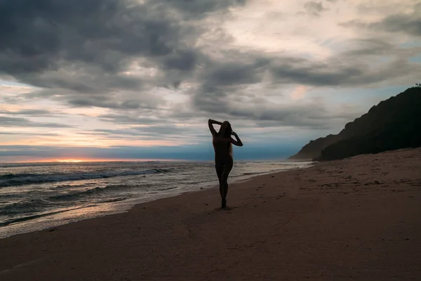 Frontansicht Silhouette einer attraktiven Frau. schönes junges Mädchen mit langen Haaren, das am Strand spaziert und bei Sonnenuntergang posiert. Konzept des Reisens, der Entspannung, des Yoga — Stockfoto