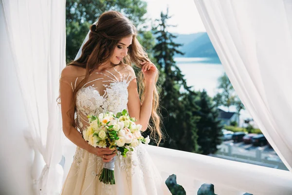 Porträtt av vackra unga bruden med söt smite i vit bröllop klänning håll bukett blommor i hennes händer. Begreppet kläder och familj — Stockfoto