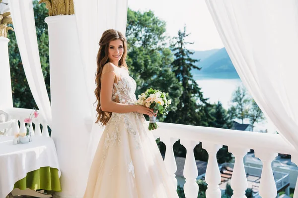 Retrato de hermosa novia joven con lindo smite en vestido de novia blanco sostienen ramo de flores en sus manos. Concepto de ropa y familia —  Fotos de Stock