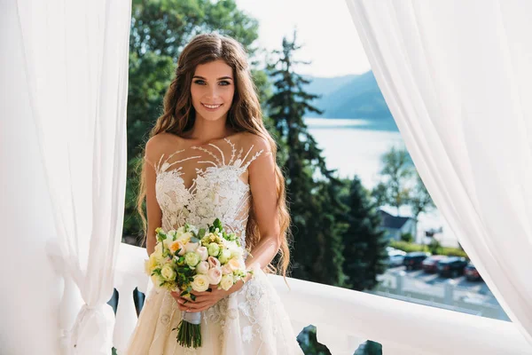 Hübsche Braut mit schönem Blumenstrauß in den Händen. attraktive junge Frau im weißen Kleid mit Hochzeitsschminke auf grünem Gras-Hintergrund. Nahaufnahme Porträt lächelnde Braut — Stockfoto