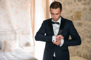 güzel siyah ceket ve beyaz gömlek zarif damat kol düğmeleri eline Giydir. Klasik giysiler içinde bir iş adamı. Esmer bir adam bir düğün gününde sabah bir düğün için hazırlanan.
