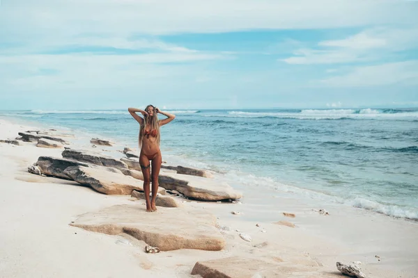 Sexy chica joven tatuada en traje de baño rojo posando en la playa. Hermosa mujer rubia con el pelo largo y buen cuerpo deportivo relajante en el océano. Concepto de modelo deportivo, trajes de baño . — Foto de Stock