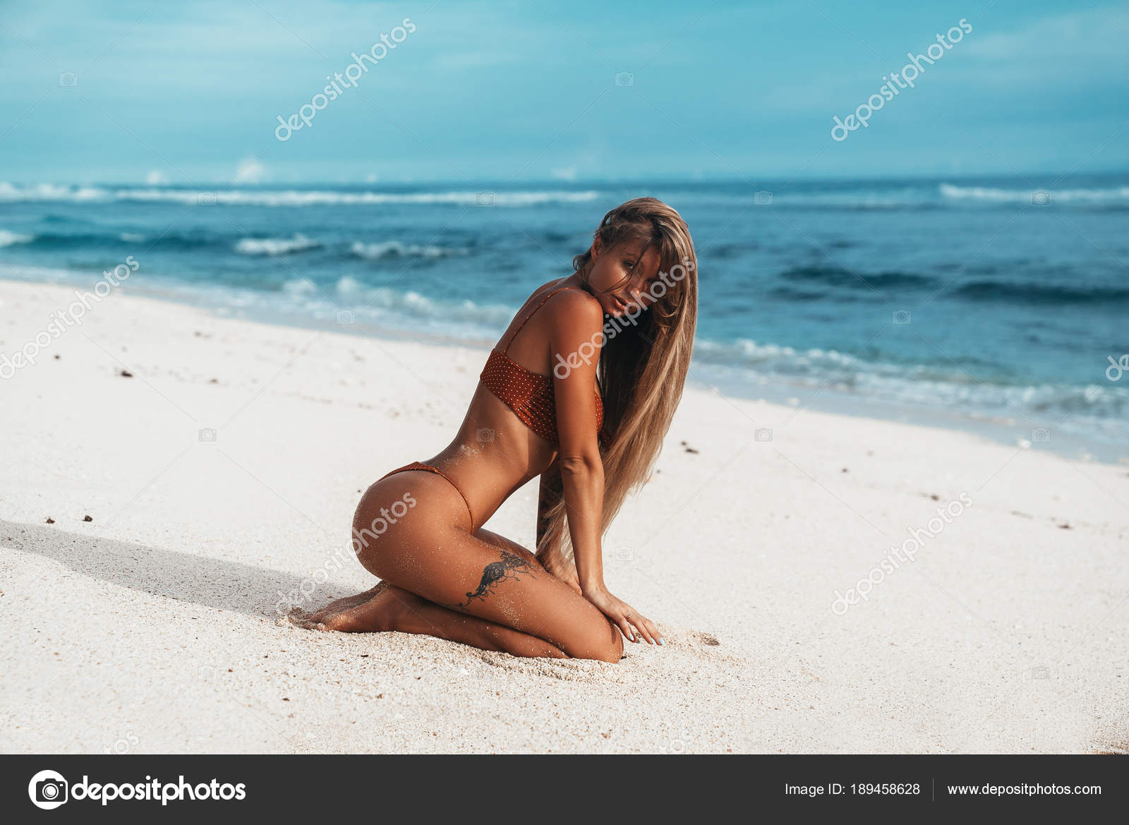 Sexy girl with a tattoo on her leg rests on the beach picture