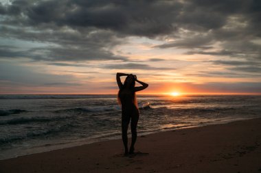 Önden Görünüm çekici kadın silüeti. Gün batımında poz güzel genç kız Sahilde yürüyüş uzun saçlı. Genel kavram-in seyahat etmek, sakin ol, yoga