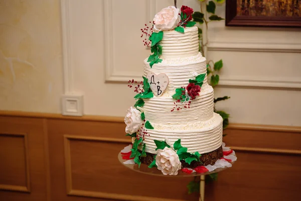 Білий багаторівневий весільний торт, прикрашений червоними та зеленими кремовими квітами — стокове фото