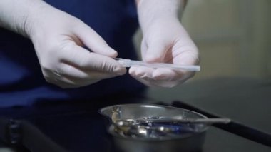 Cerrah büyük metal iğne tıbbi tepsisinden alır. Doktor tıbbi malzeme steril eldiven inceliyor. Varis manevra için iğne.