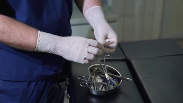 Αρσενικό γιατρός σε αποστειρωμένα γάντια βγάζει ιατρικές χαρτοπετσέτες από το πακέτο και αυτό εισάγει το σφιγκτήρα πριν την επέμβαση. Κοντινό πλάνο χειρούργο χεριών με ιατρικά εργαλεία, εξοπλισμός σε μια κλινική και — Αρχείο Βίντεο