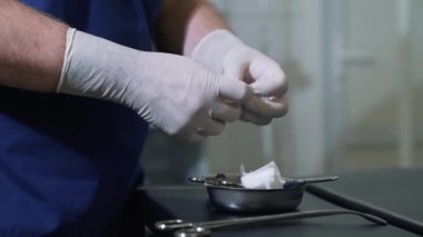 Steril eldiven erkek doktor tıbbi peçete paketinden dışarı alır ve bu işlemi önce kelepçe ekler. Tıp aletleri ellerle cerrah, bir klinikte ekipmanları kadar yakın ve