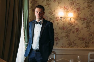 sıkı bir takım elbise ile beyaz bir gömlek ve bir papyon bir düğün gününde sabah elbiseler içinde zarif damat. İşadamı klasik giysiler.