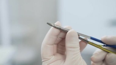 Tıp aletleri cımbız hastanede doktor steril beyaz eldiven yakından inceliyor. cerrah profesyonel kıyafetlerini giymiş elinde kelepçe inceliyor.