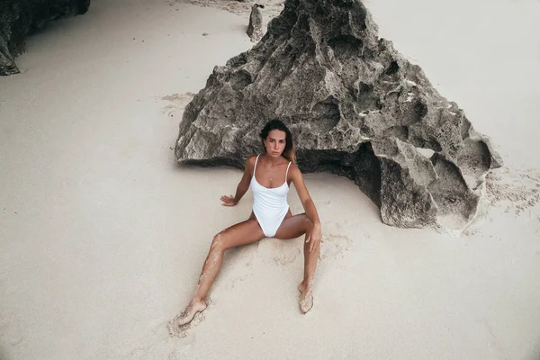 Sexy jonge meisje in witte zwembroek poseren op het strand. Mooie blonde vrouw met lange haren ontspannen aan de Oceaan. Concept van sportieve model, badmode — Stockfoto