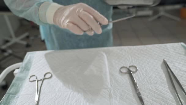 Dicht, neemt de chirurg medische instrumenten in zijn arm uit de chirurgische tabel. Dokter nemen steriele hulpmiddelen in het ziekenhuis. Bereiding van medische apparatuur voor de operatie. Het begrip gezondheid — Stockvideo