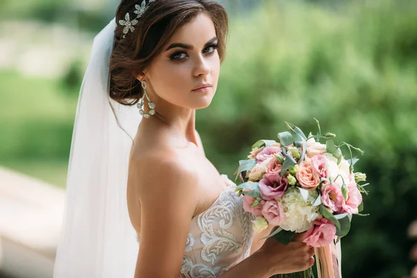 Nahaufnahme, Porträt Luxus Braut mit Braut Make-up und Frisur in der Ehe. erstaunliche Mode-Modell in wunderschönen weißen Brautkleid mit Blumenstrauß in ihren Händen. Konzept der Familie. — Stockfoto